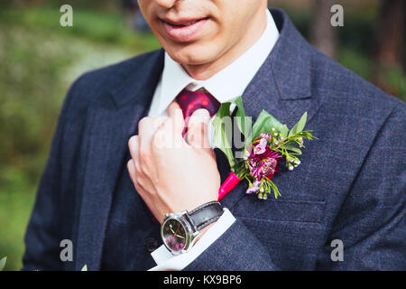 Groom in a jacket, The groom straightens the buttonhole, wedding day Stock Photo