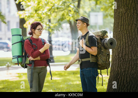 Teenagers tourists with backpacks - smoking and standing in the park at summer midday Stock Photo