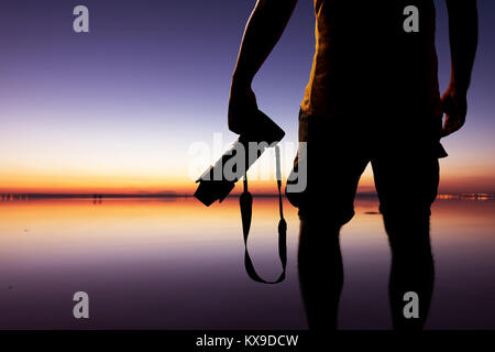 Male photographer taking picture with dslr camera on the beach at sunset time Stock Photo