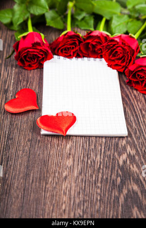 Red roses and card on a  wooden background. Greeting card with Valentine's Day, Birthday or Wedding. Stock Photo