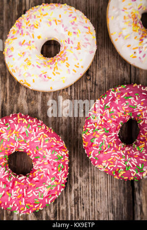 Multicolored donuts close-up on a wooden background. Delicious dessert. Stock Photo