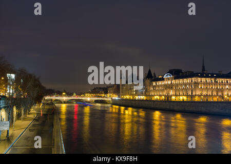 Night view of Conciergerie Castle and Pont Notre-Dame bridge over river Seine. Castle Conciergerie is a former prison located on west of the Cite Isla Stock Photo