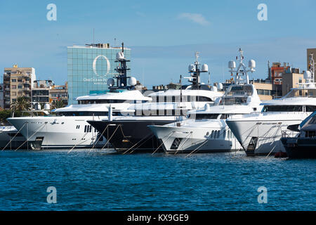 Luxury yachts and motor cruisers moored in  v, Barcelona, Catalunya, Spain. In the background is the 'One Ocean Port Vell' apartment building. Stock Photo