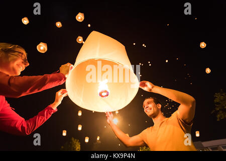 Two people releasing a traditional flying lantern at Yi Peng / Loy Krathong festival in Chiang Mai, Thailand Stock Photo