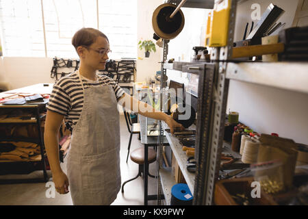 Female worker taking tools from shelf Stock Photo