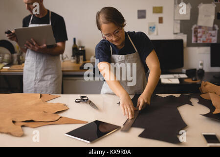 Worker measuring leather with ruler in workshop Stock Photo