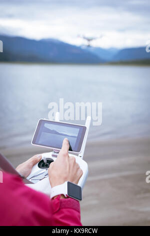 Two hands on remote control controlling drone Stock Photo