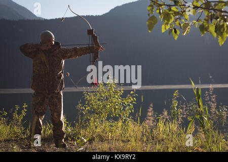 Archer with a bow and arrow aiming in the twilight Stock Photo - Alamy