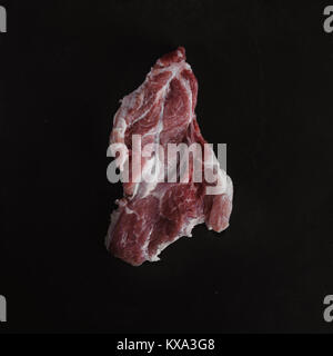 Food photo in rustic style. Raw meat. Pork steak on dark black background of slate plate. Top view. Flat lay. Stock Photo