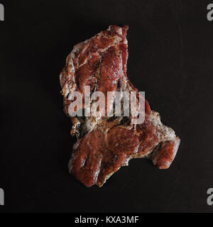 Food photo in rustic style. Marinated meat. Pork steak on dark black background of slate plate. Top view. Flat lay. Stock Photo