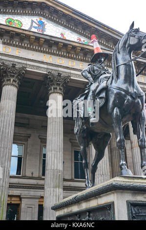 Famous equestrian statue of Duke of Wellington  with a road cone on his head, and a Santa hat during the festive period, in front of the GoMA. Stock Photo