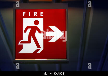 The emergency sign for fire shows the direction of flame. The riskly exit for fire board hangs on the ceiling of the building. Stock Photo