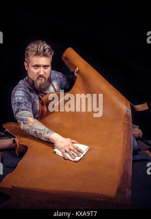 Leather master demostrating leather cutting process in the workplace Stock Photo