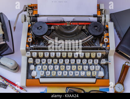 Old typewriter on a white background with a lot of items around and typed words "It all starts with  " Stock Photo