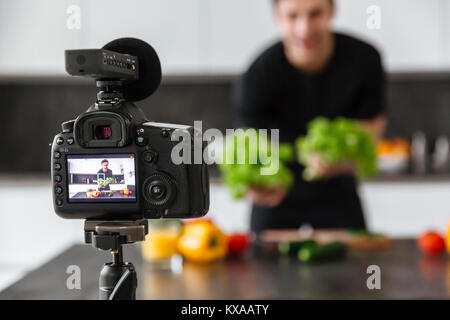Close up of a video camera filming young male blogger at the kitchen Stock Photo
