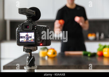 Close up of a video camera filming young man blogger at the kitchen Stock Photo