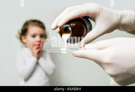 Sick little girl awaits her medication pouring in a spoon Stock Photo