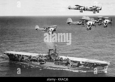 The aircraft carrier HMS Ark Royal with a flight of Swordfish overhead Stock Photo