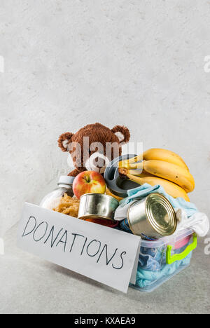 Plastic donation box with toys, clothes and food, white grey background copy space Stock Photo