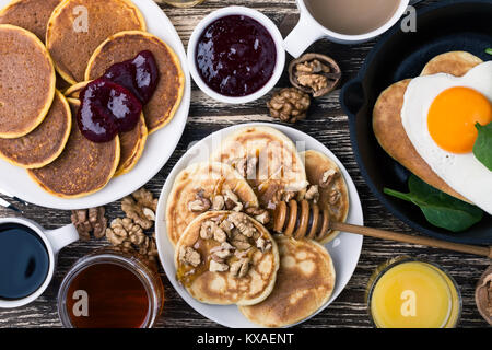 Valentine's day breakfast or brunch. Homemade  heart shape fried egg and pancake in cast iron skillet  with spinach, pancakes with jam, orange juice Stock Photo