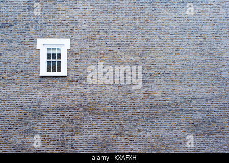 Small white window on a big brick empty wall Stock Photo