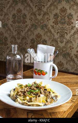 Plate of beef stroganoff, bottle of water and cutlery in mug placed on wooden table, Portland, Oregon, USA Stock Photo