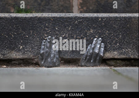 Two mysterious metal hands come out of a crack of a curb of the cathedral of St. Bartholomew in Pilsen, Czech Republic, on January 8, 2018. Officially, nobody knows who gave it into a crack about the end of the last year, or whether it have any meaning. (CTK Photo/Miroslav Chaloupka) Stock Photo