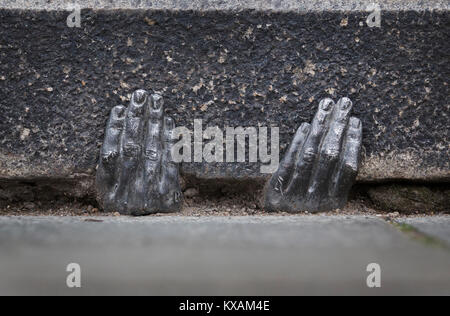 Two mysterious metal hands come out of a crack of a curb of the cathedral of St. Bartholomew in Pilsen, Czech Republic, on January 8, 2018. Officially, nobody knows who gave it into a crack about the end of the last year, or whether it have any meaning. (CTK Photo/Miroslav Chaloupka) Stock Photo