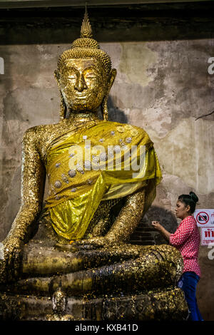 Thai worshiper making offering to the Statue of Buddha, Ordination Hall, Bang Kung Camp, Samut Songkhram, Thailand.