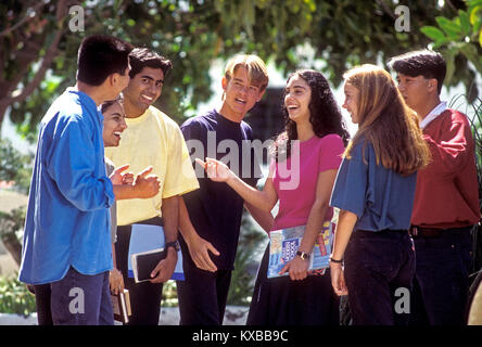Multicultural School college group of 7 happy attractive teenage senior school college high school multicultural students in colourful t shirts relaxing talking and interacting outside in a sunny school college campus environment Stock Photo
