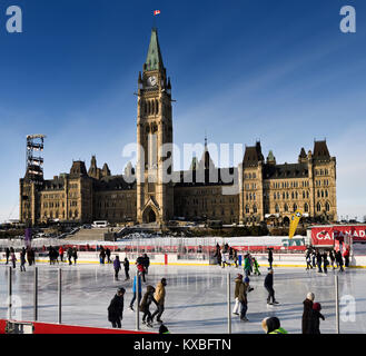 Parliament Hill Centre Block Peace Tower with afternoon sun on skaters on the Canada 150 Rink outdoors in winter Ottawa Stock Photo