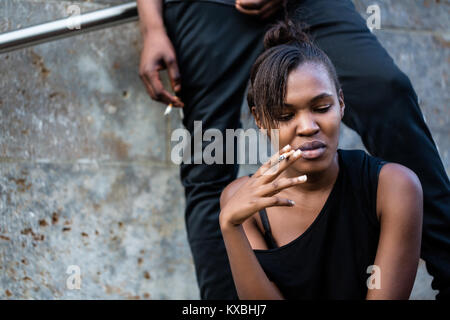 Young African American woman and man smoking outdoors in the cit Stock Photo