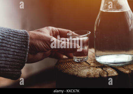 Man drinking strong alcohol drink from a shot glass, close up of hand, selective focus Stock Photo