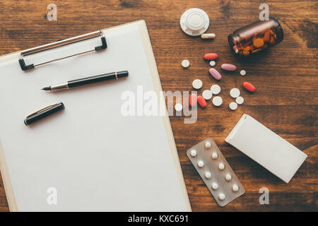 Overhead view of medical doctor office desk with note pad clipboard and prescription drugs Stock Photo