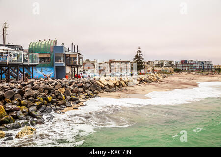 Waves, stones at the coastline with houses in background, Swakopmund German colonial town, Namibia Stock Photo