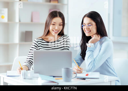 Cheerful female colleagues working on project Stock Photo