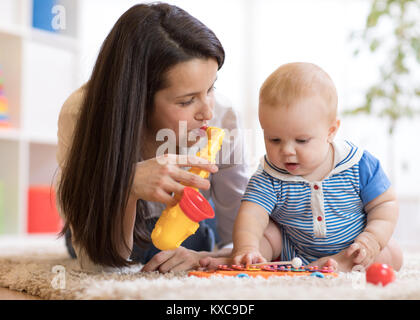 Woman and baby playing musical toys in nursery Stock Photo