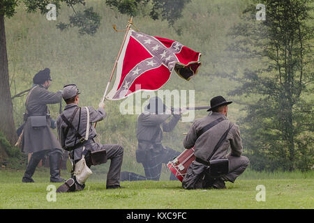 A group of four confederate soldiers firing weapon with a southern flag at a reenactment Stock Photo