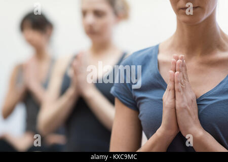 Women practicing yoga and mindfulness meditation together, they are clasping hands and relaxing, healthy lifestyle and spirituality concept Stock Photo