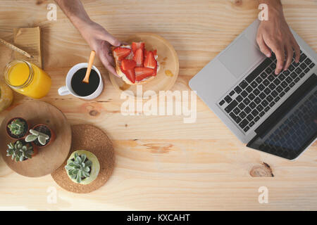 Young man using laptop while having breakfast Stock Photo