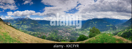 Panoramic view of the city of Merano from the mountain station of the Hochmuth cable car in the direction of Bolzano with blue and cloudy skies in sum Stock Photo