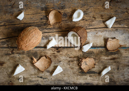 Fresh coconuts with spreaded chops and shell parts on wooden background Stock Photo