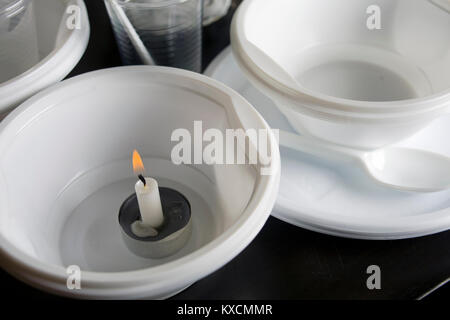 Various plastic tableware with a candle inside of disposable plate, closeup still life Stock Photo