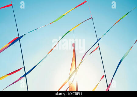 colorful strips of cloth tied to poles flying in wind on sunny spring day at kite festival Stock Photo