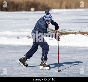 Teenage boy playing ice hockey on a pond on a cold winter day Stock Photo