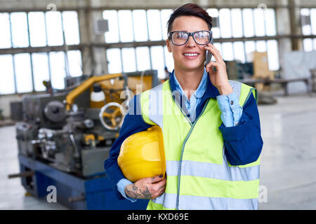 Female Worker Speaking by Phone at Factory Stock Photo