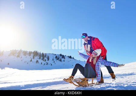Young Couple Sledding And Enjoying On Sunny Winter Day Stock Photo