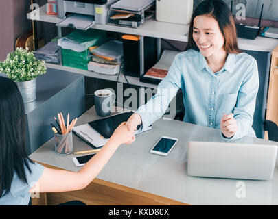 Two businesswoman handshake in causal meeting at home office desk about business planing,business teamwork,top view of asian business consulting toget Stock Photo