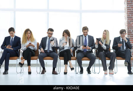 employees with smartphones sitting in the lobby Stock Photo