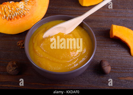 Bowl with pumpkin puree, surrounded by pieces of pumpkin Stock Photo